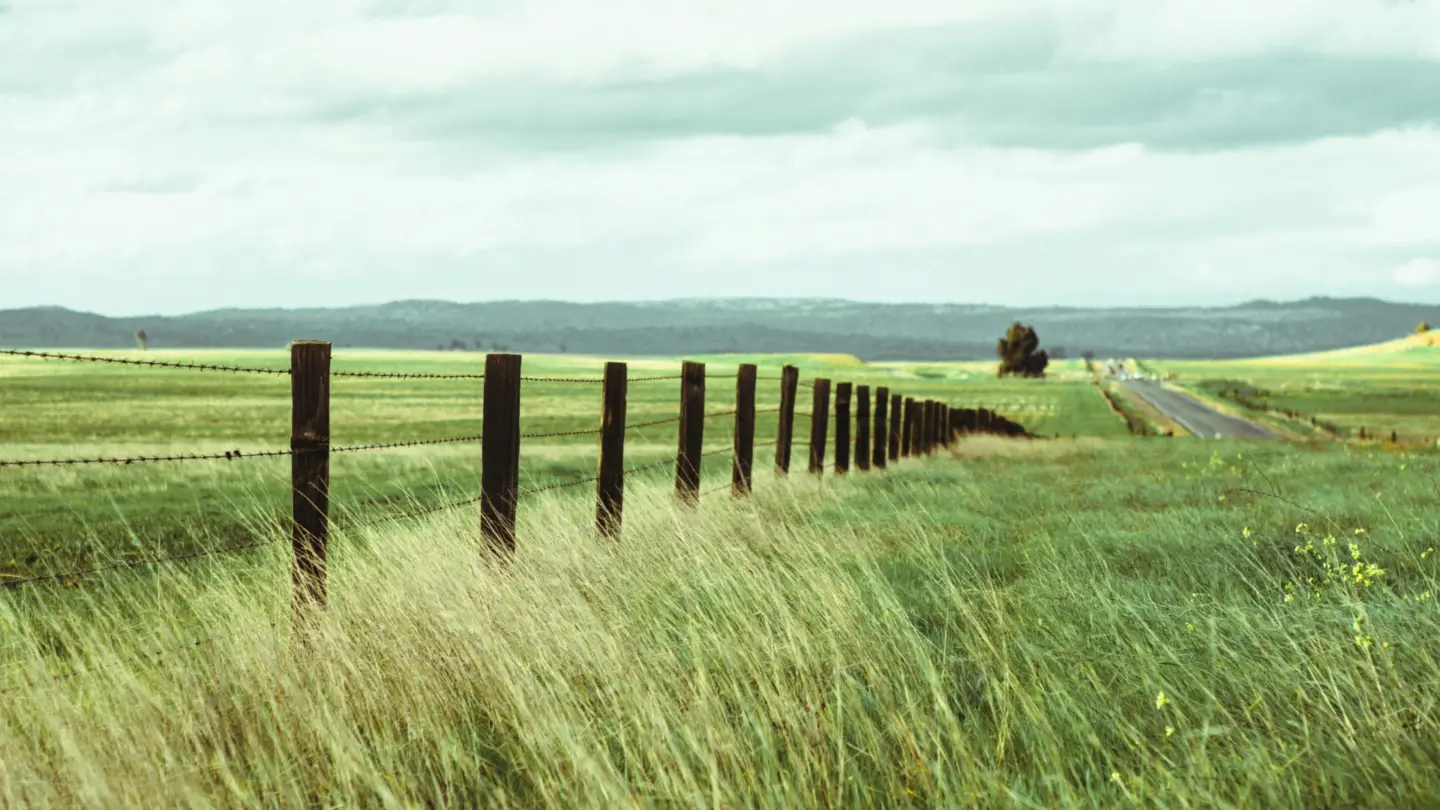 Agricultural barbed wire security farm fence with overlooking view featuring cloudy sky in miami valley oh