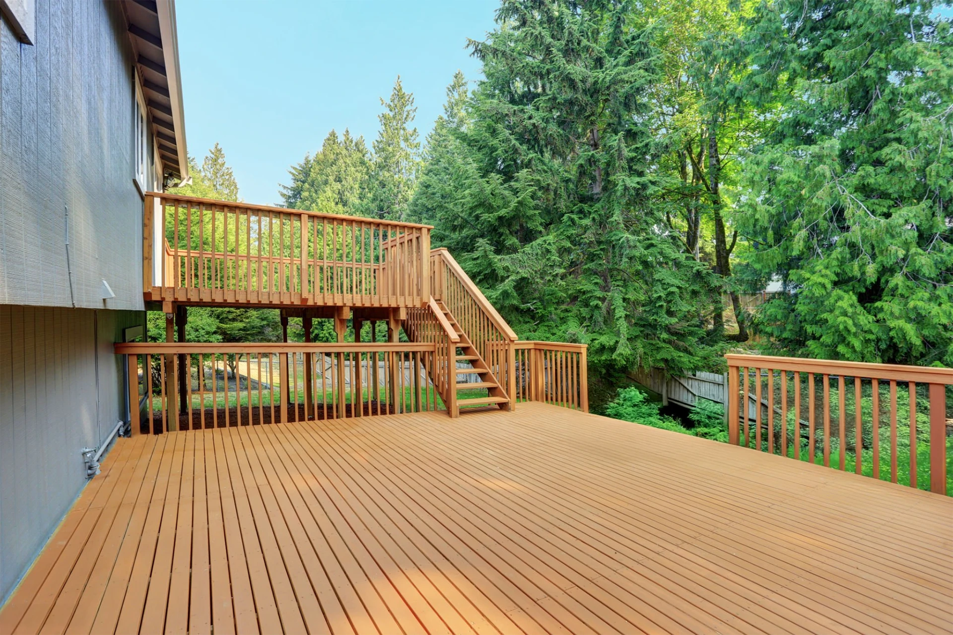 Backyard view of grey rambler house with upper and lower composite decks in miami valley oh