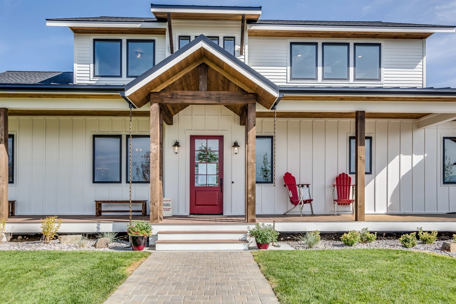 Black trim windows and red front door on white house with porch and chairs on it in miami valley oh