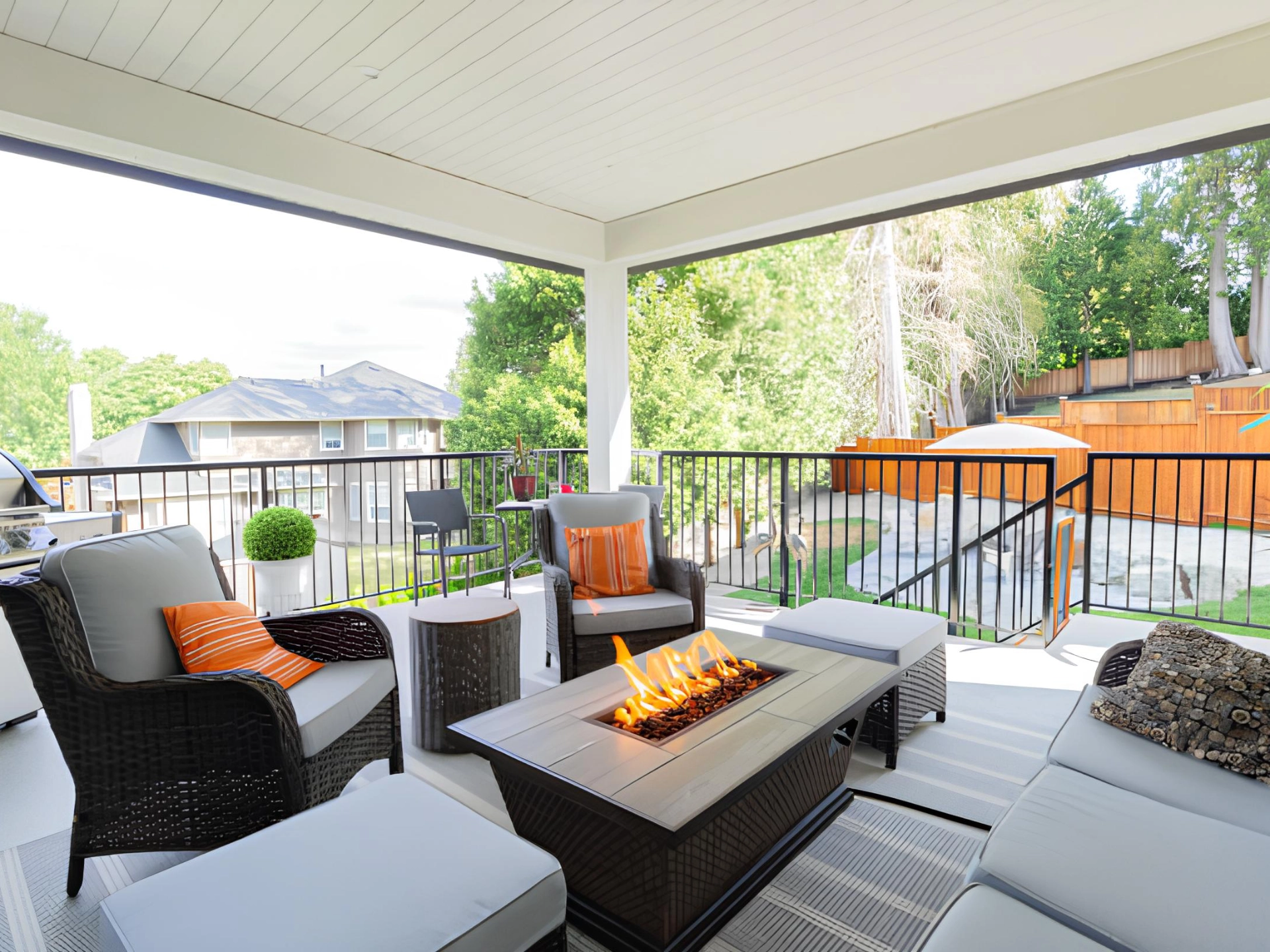 Covered deck with a firepit and couch with black metal railing in miami valley oh
