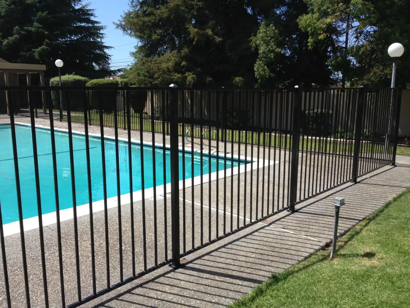 High aluminum pool fence with post cap lights and tall trees on the background in miami valley oh