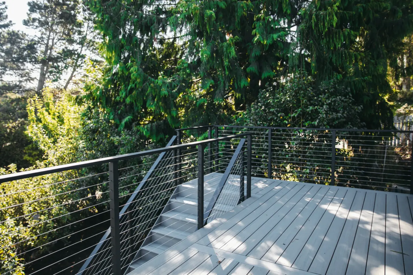 Modern composite deck with cable deck railing and overlooking green trees and forest in miami valley oh