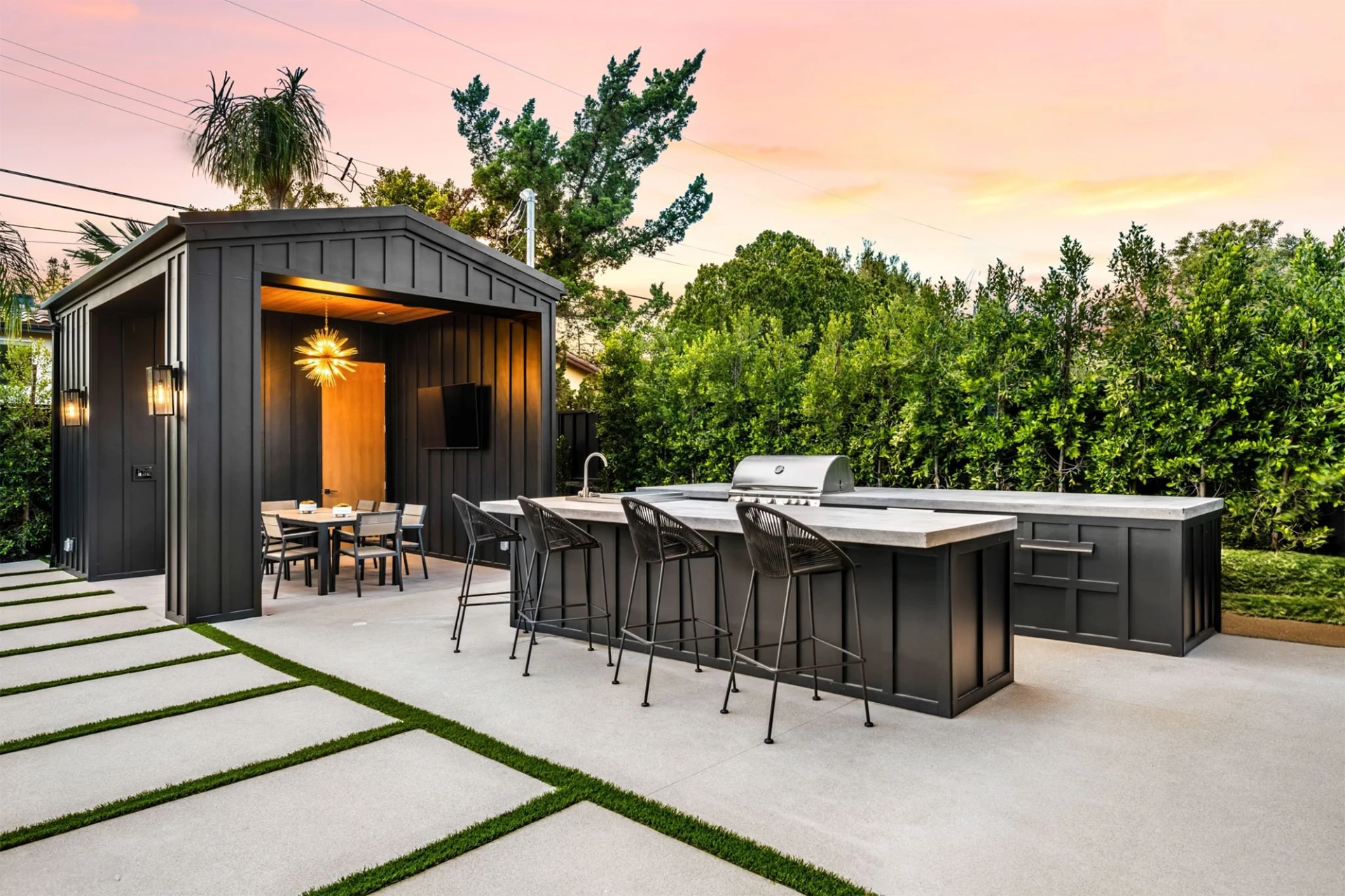 Modern outdoor living kitchen and dining area at sunset featuring trees on the background in sunset in miami valley oh