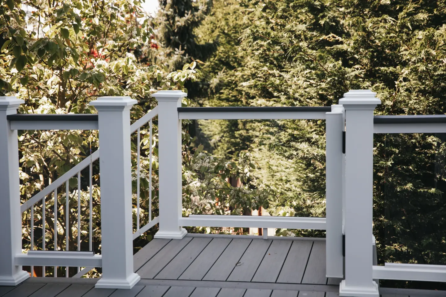 Modern white deck railing with horizontal metal balusters on composite deck overlooking lush green trees and foliage in miami valley oh