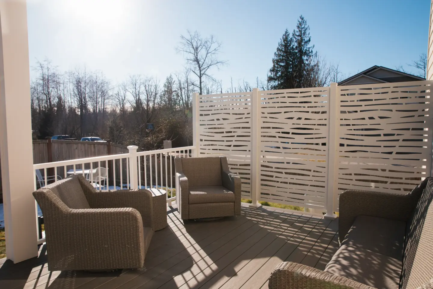 Outdoor patio with wicker chairs and modern white privacy screen providing secluded backyard seating area featuring clear sky view in miami valley oh